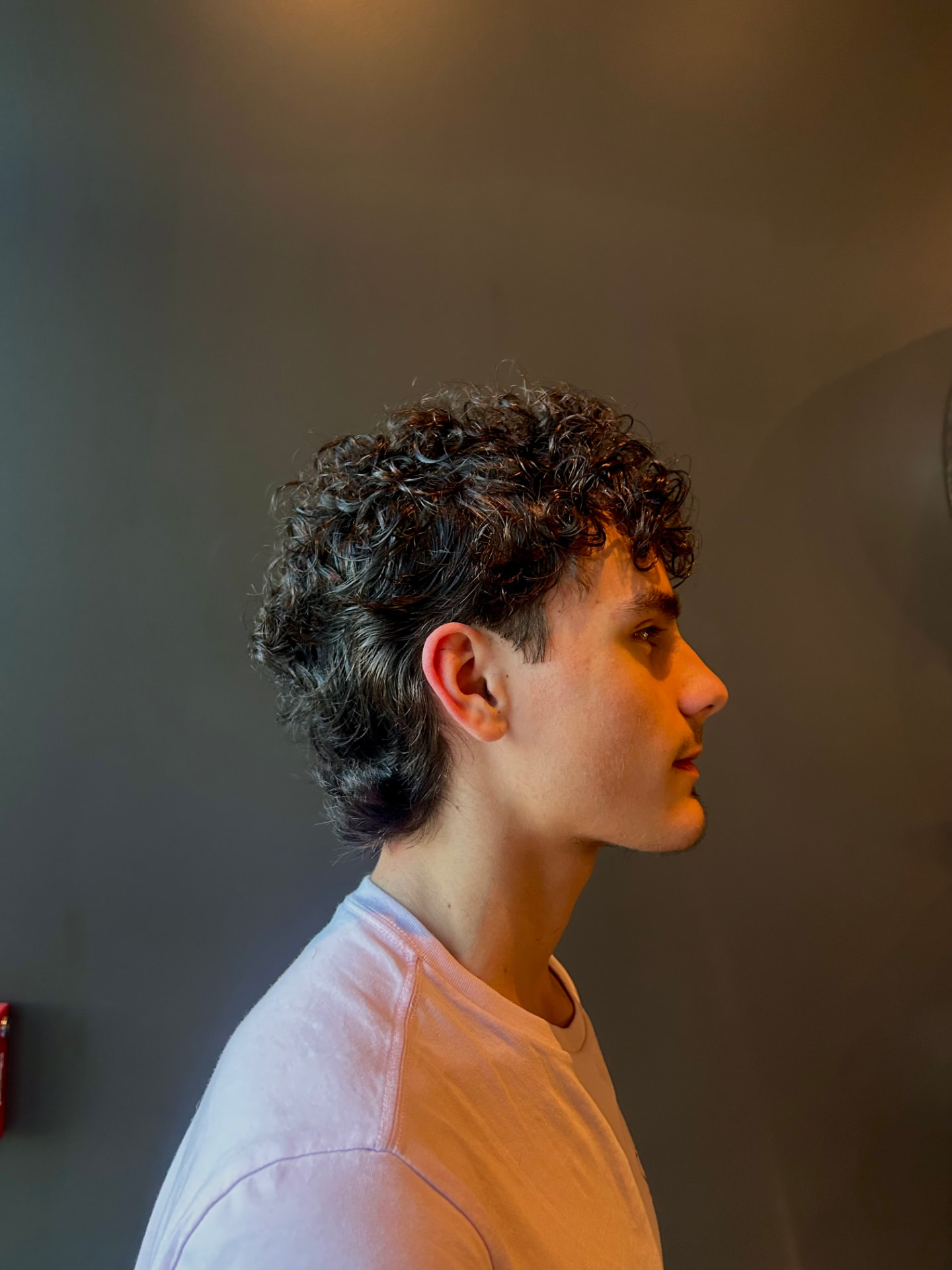 Curly mullet with a tapered fade around the ear at The Cave, Rogers AR