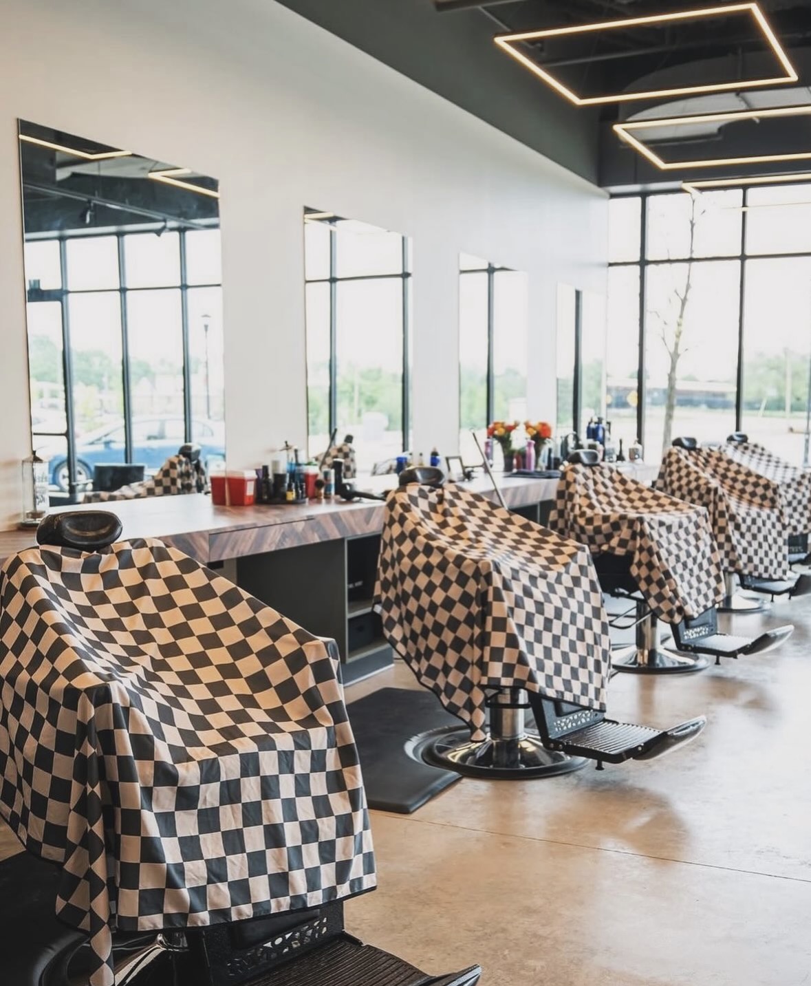 Row of barber chairs draped in checkered capes along the mirrored stations at The Cave, Springdale AR